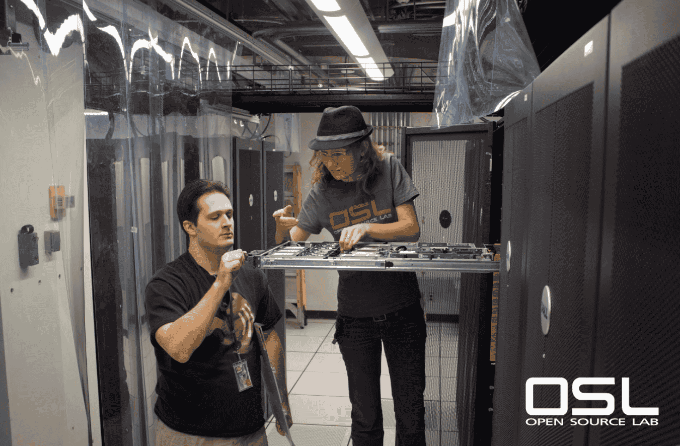 a photo that shows two people working on a server rack with the osl white logo towards the bottom-right