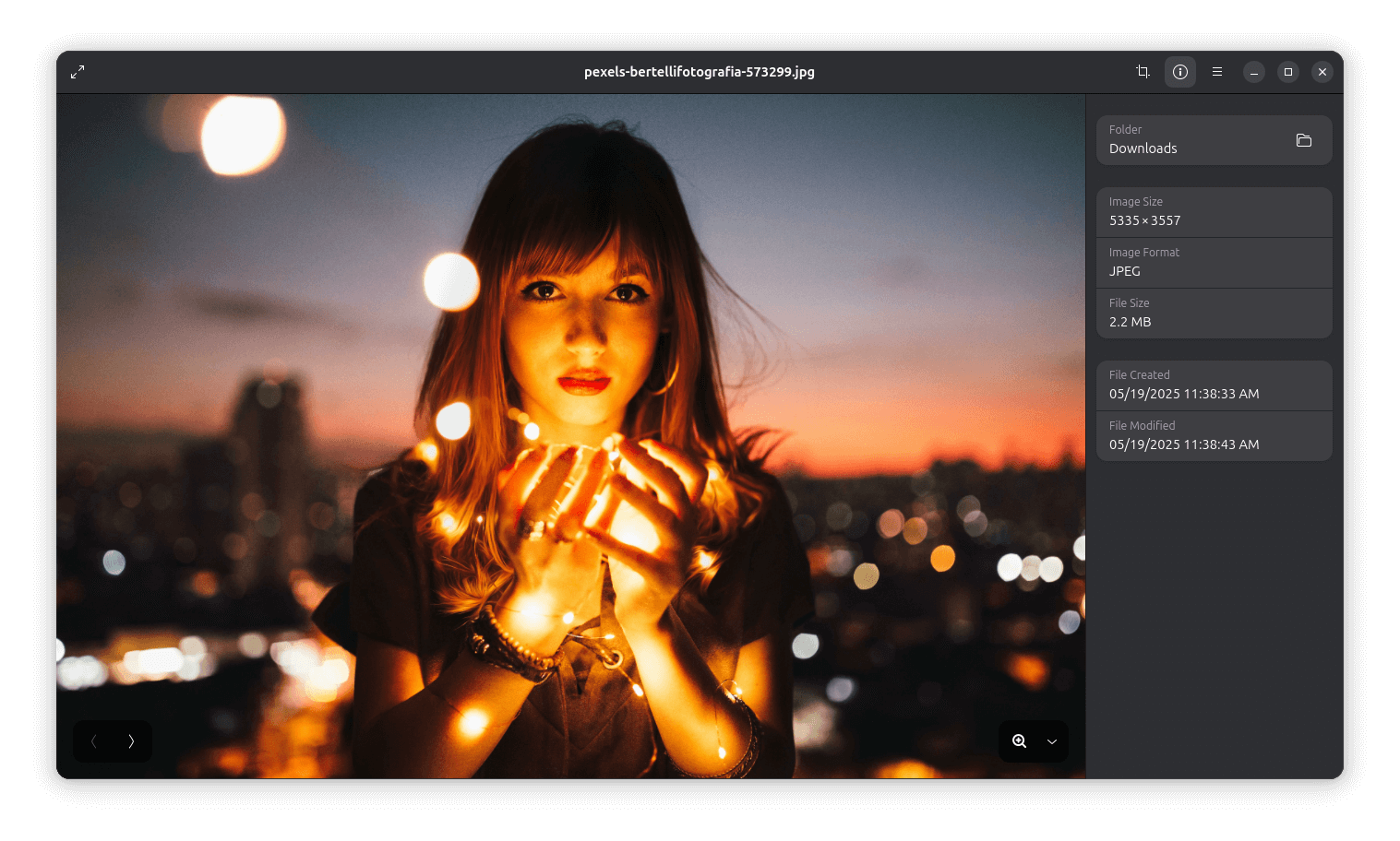 loupe being used to show an image of a woman holding fireflies with a cityscape in the background