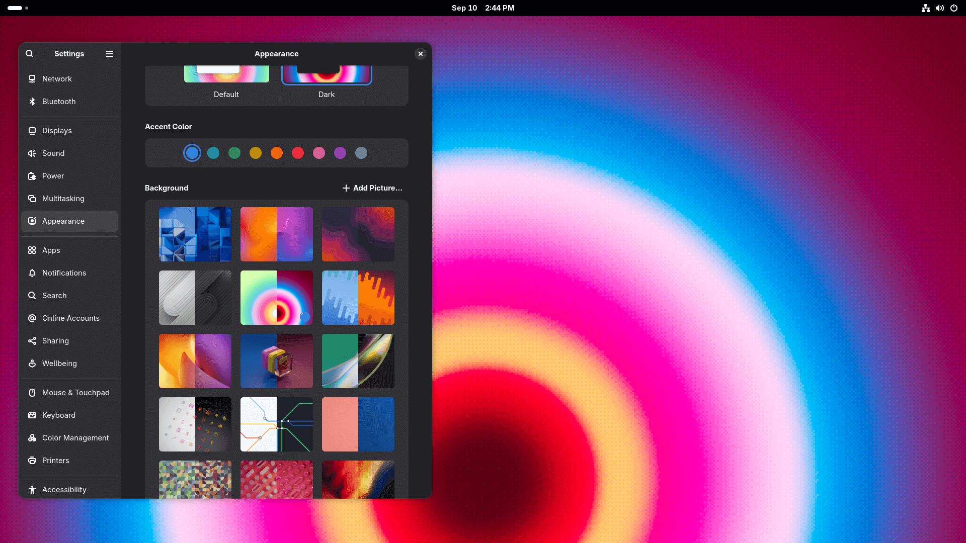 the appearance menu is open on gnome 49 showing many new wallpaper options, one of them is set as the wallpaper for this specific system, it has many shades of pink, blue, yellow, and white in it in a circular pattern
