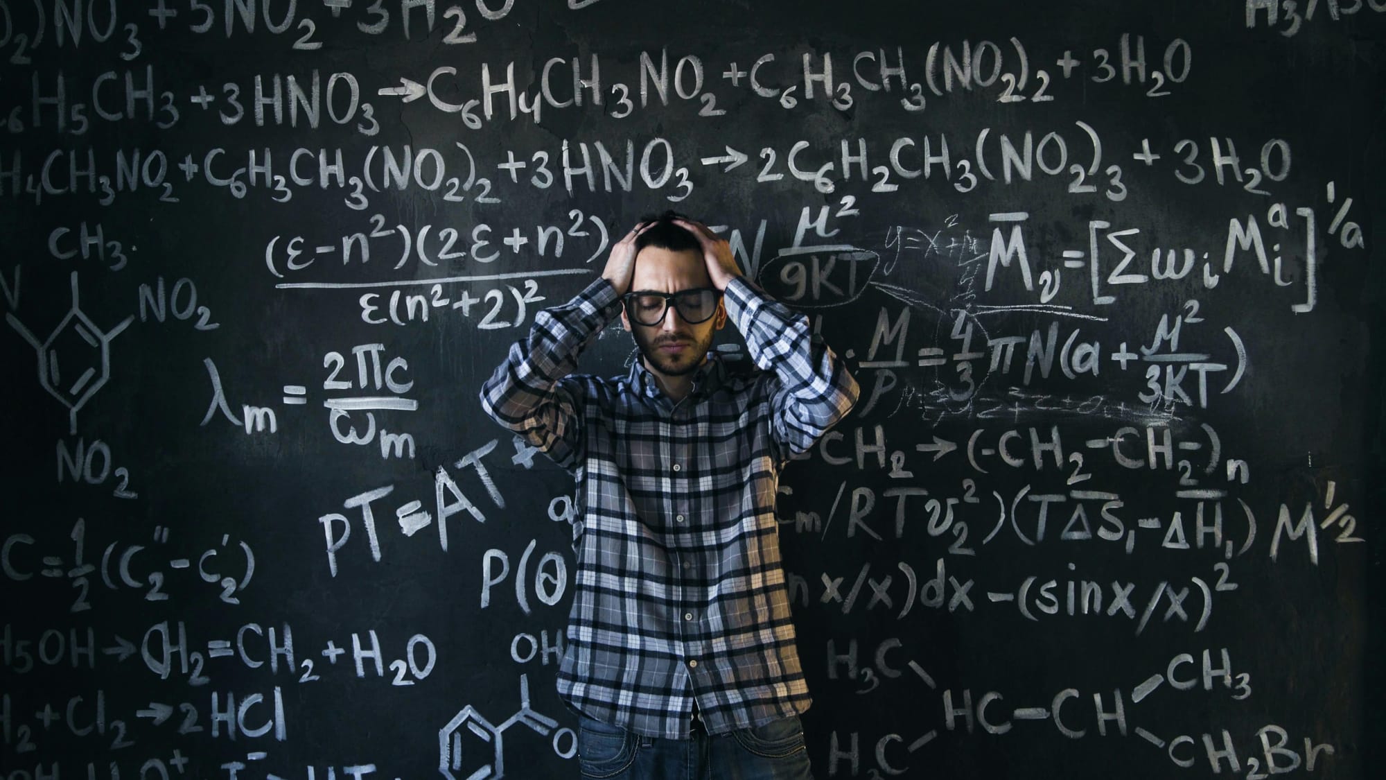 A photo of a person surrounded by chemical formulas and holding their head with their eyes closed, expressing confusion and overwhelm