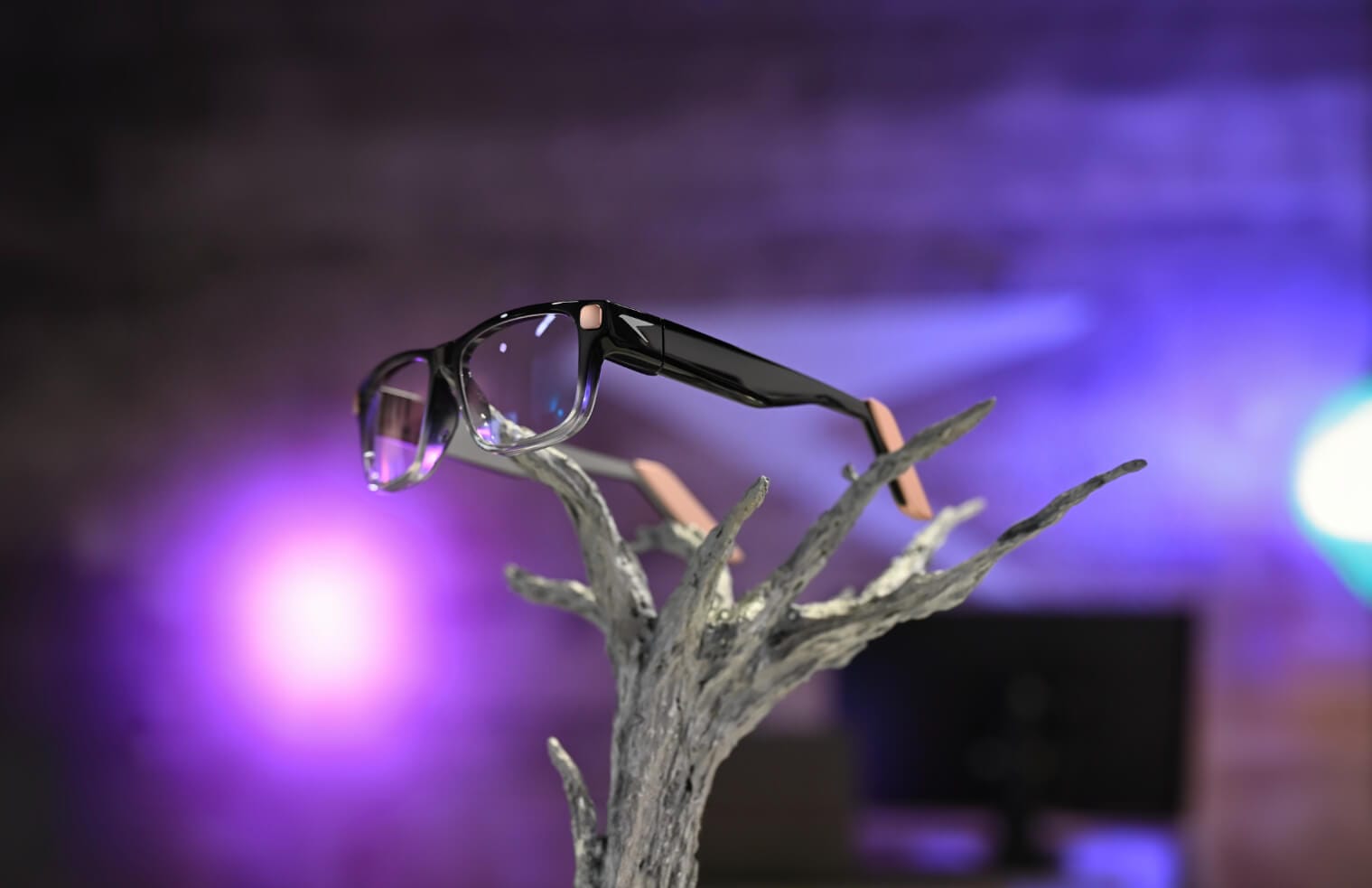 a raven prism smart glass is seen at the center of this image sitting on a tree branch stand