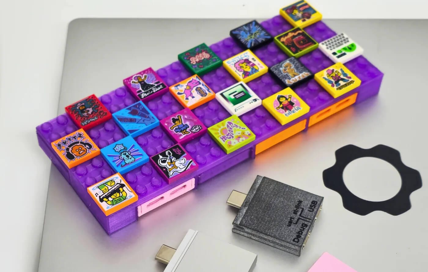 laying on a white table is a framework laptop, over which two expansion cards and a purple-colored dockframe usb-c hub are placed